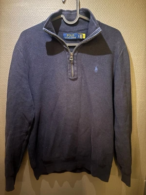Mörkblå halvzip tröja Polo Ralph Lauren - Tja! Jag säljer en snygg mörkblå tröja från Polo Ralph Lauren med halv dragkedja och broderad logga på bröstet. Tröjan har hög krage, långa ärmar och ribbade muddar. Perfekt för en stilren och avslappnad look. Bara att höra av sig vid funderingar:) (TRÖJAN ÄR EJ SOLBLEKT!)