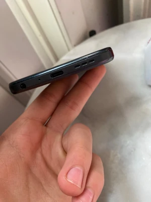 Svart smartphone med USB-C och hörlursuttag - Säljer en svart smartphone med USB-C-port, högtalargaller och 3,5 mm hörlursuttag. Telefonen har en slimmad design med rundade kanter och knappar på sidan. Passar perfekt för dig som vill ha en enkel och stilren mobil.