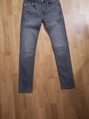 Gråa skinny jeans  - Säljer ett par helt nya gråa skinny jeans med hög midja och klassisk femficksdesign. Jeansen har smal passform hela vägen ner och är tillverkade i stretchigt denimtyg för extra komfort. Perfekta för en trendig och avslappnad look.