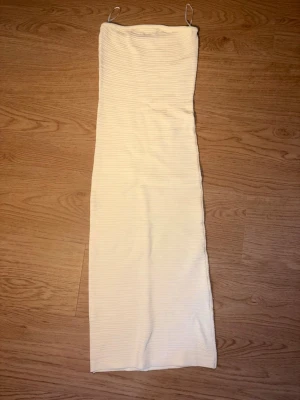Vit ribbad klänning  - Säljer en stilren armlås klänning med ribbad struktur. Klänningen har en rak passform och är ärmlös, perfekt för sommarens alla tillfällen. Enkel och trendig design som är lätt att matcha med accessoarer.
