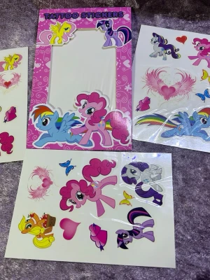 Tatueringsstickers med My Little Pony & Disney - Färgglada tatueringsstickers med motiv från My Little Pony och Disney-karaktärer som Mickey och Minnie Mouse. Perfekt för att dekorera huden eller accessoarer. Innehåller flera ark med olika figurer, hjärtan och regnbågar i rosa, blått, gult och lila. 75kr/paket /bild 