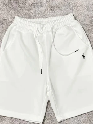 Vita shorts med snörning från Polo Ralph Lauren - Snygga vita shorts från Polo Ralph Lauren med elastisk midja och snörning. Klassisk svart logga broderad på ena benet och två sidofickor. Perfekta för sommaren och riktigt clean look.