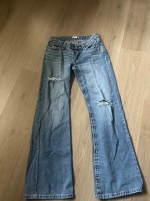 Blå slitna loose wide jeans - Ett par ljusblå loose jeans med slitningar på båda benen och klassiska fem fickor. Jeansen har en avslappnad passform och är tillverkade i denim. Perfekta för en trendig och avslappnad stil. Knappt använda. Väldigt bra skick! Jag är 158 och dem är perfekta i längden! 