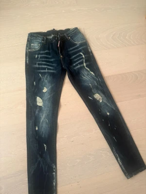 Mörkblå slitna skinny jeans - Säljer ett par mörkblå skinny jeans med slitningar och distressed detaljer framtill och baktill. Jeansen har klassisk femficksmodell och låg midja. Materialet är denim med stretch för skön passform. Perfekta för en trendig och avslappnad look. För 13-14 år