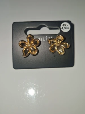 Guldiga blomformade örhängen - Snygga örhängen från Montini (ur&penn), de är guldiga o har en söt blomform💘 aldrig använda!! ordinarie pris 50kr men säljer för 25kr!!