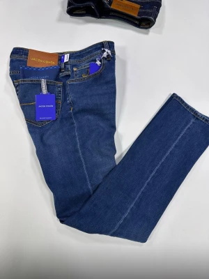 Blå jeans från Jacob Cohën (MED TAGS MM) - (ÄKTA SÅKLART!!!!!!!).                                                Snygga blå jeans från Jacob Cohën med klassisk femficksdesign och raka ben. Jeansen har kontrastsömmar och patch i läder baktill i midjan. Perfekta för en stilren och avslappnad look.