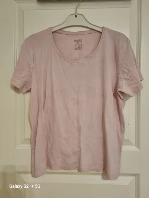 Ljusrosa t-shirt från Esmara XL - Enkel och stilren ljusrosa t-shirt från Esmara i storlek XL. T-shirten har rund halsringning och korta ärmar. Tillverkad i mjuk bomull som känns skön mot huden. Perfekt basplagg till garderoben.
