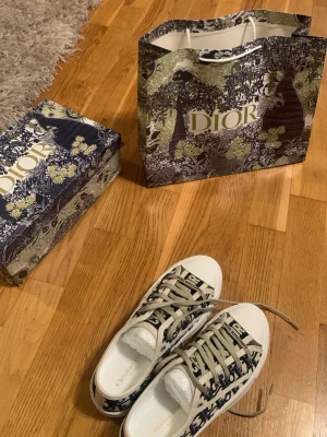Dior Oblique låga sneakers - Snygga låga sneakers från Dior med klassiskt blått och vitt Oblique-mönster. Skorna har vita gummisulor, beige snören och detaljer i canvas. Perfekta för dig som vill ha en exklusiv och trendig look.