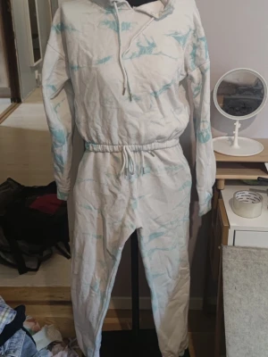Vit och blå tie-dye loungewear set - Mysigt loungewear set i vitt med ljusblå tie-dye detaljer. Setet består av en hoodie med dragsko och långa ärmar samt matchande byxor med resår i midjan och vid anklarna. Perfekt för chill dagar hemma.