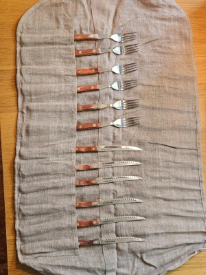 Bestickset med trähandtag i tygfodral, NYTT  - NYTT set med sex knivar och sex gafflar med trähandtag, snyggt förvarade i ett grått tygfodral som går att rulla ihop och knyta. Perfekt till picknick eller camping. Besticken har metallblad och klassisk design.