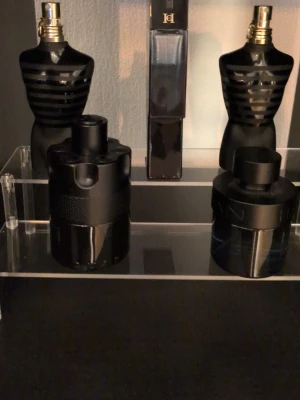 Svarta parfymflaskor i unik design - Samling av exklusiva parfymer med eleganta flaskor i guld och glas. Flera flaskor har geometriska former och detaljer som metall, krona och reliefmönster. Designen är modern och sticker ut med glänsande ytor och unika lock. (Intresse koll) Säg till så kan vi komma överens om bra pris, fler köp bättre pris.