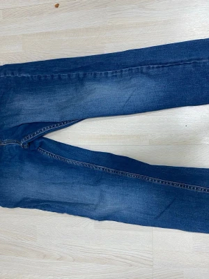 Mörkblå jeans från Lee - Snygga mörkblå jeans från Lee med klassisk femficksdesign och gulbruna kontrastsömmar. Jeansen har en rak passform och är tillverkade i slitstarkt denimtyg. Perfekta för dig som gillar en tidlös och enkel stil.
