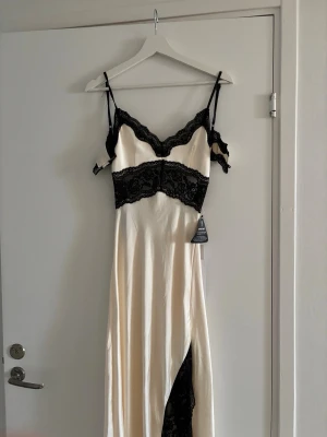 Satinklänning med spets - Eftertraktad klänning från Gina Tricot, champagne med svart spets och högre slits. Pris 1000kr Ny med prislapp🥰