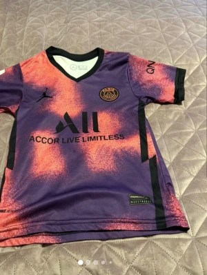 PSG Messi matchtröja lila/orange - Säljer en PSG matchtröja med Messi 30 på ryggen. Tröjan har en cool lila och orange design med svarta detaljer och klubbmärke på bröstet. V-ringad hals och korta ärmar. Perfekt för fotbollsfans som vill sticka ut på läktaren eller planen.