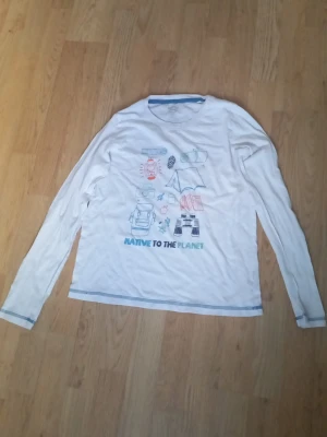 Vit långärmad topp med tryck - Vit långärmad topp med färgglatt campinginspirerat tryck och texten 'NATIVE TO THE PLANET' framtill. Rund halsringning och blå sömdetaljer vid ärmslut och nederkant. Perfekt för en avslappnad och chill stil.