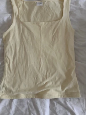 Ljusgult linne från Gina Tricot - Ljusgult linne från Gina Tricot med fyrkantig ringning. Använd två gånger så fortfarande bra skick.
