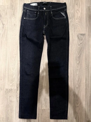 Replay Anbass Hyperflex Dry Jeans Mörkblå W31/L32 - Slim Fit - Replay Anbass Hyperflex Dry mörkblå jeans i stretchig Hyperflex denim med slim fit passform som sitter snyggt och bekvämt och funkar till allt, storlek W31/L32 (ursprungligen L34 men uppsydda), midja 38 cm, ytterbenslängd 102 cm, benöppning 15 cm, modellen är 185cm & väger 65kg, i fint skick.