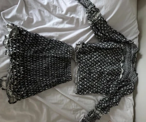 Svartvit blus med volang och mönster - Supersöt svartvit blus med långa ärmar och volangdetaljer. Blusen har ett tättsmockat mönster och elastiska partier som ger en snygg passform. Perfekt för dig som gillar unika toppar med mycket detaljer. Det är ett  sett men skriv ifall ni skulle vilja köpa en av delarna separat💓