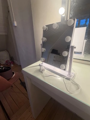 Sminkspegel med LED-belysning - Snygg sminkspegel med vit ram och justerbart stativ. Den har tre olika ljus varmt,kallt och medel. Spegeln har åtta runda LED-lampor längs kanterna som ger bra ljus för sminkning. Drivs med USB-sladd som medföljer. Perfekt att ha på sminkbordet för en tydlig och jämn belysning.