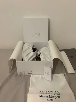 Maison Margiela GATS strl 43 svart/gummi - Säljer ett par maison margiela gats sneakers med dustbug och box som följer med. Skorna är riktigt unik och futuristisk vibe. Skorna har svarta detaljer och vita snören. Perfekta för dig som vill sticka ut och ha något annorlunda på fötterna. Passar varje sammanhang alltså om du vill klä upp dig eller vara chill. Fraktas alltid inom 24h och priset ej hugget i sten