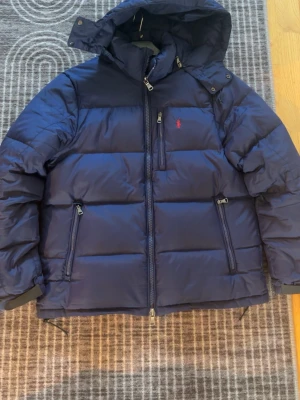 Mörkblå dunjacka från Polo Ralph Lauren - Jätte fin Polo RalphLauren jacka som e i super bra skick, men som sälj pga har en ny jacka, den värmer än jätte bra, nu när de e så kallt. Storlek L