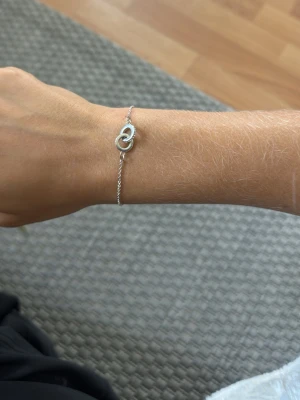 Tunt silverarmband med cirkelhänge - Säljer ett stilrent och tunt armband i silverfärg med ett minimalistiskt cirkelhänge i mitten. Kedjan är finlänkad och har ett enkelt lås. Perfekt för dig som gillar diskreta smycken med en modern touch.