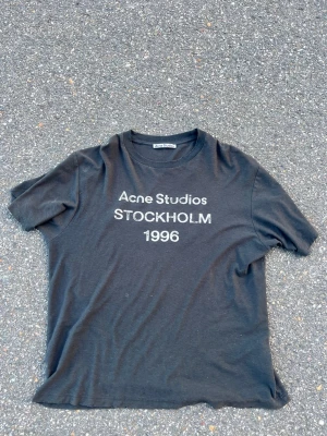 Svart Acne Studios t-shirt - Säljer en svart t-shirt från Acne Studios med trycket 'Acne Studios STOCKHOLM 1996' på bröstet. Klassisk rund hals och korta ärmar. Perfekt basplagg med clean design och skön passform.