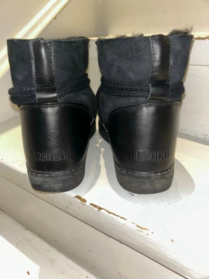 Svarta Inuikii boots - Säljer ett par svarta Inuikii boots med snörning. Skorna har en kombination av mocka och läder på utsidan samt grov sula. Perfekta för kalla dagar och riktigt snygga till vinterns outfits.