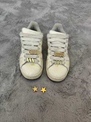Vita adidas campus  - Vita adidas campus med berlocker som tillhör skorna när man beställer skorna från adidas. Bara använde ett fårtal gånger då jag köpte fel storlek. Väldigt bra skick förutom att de är lite smått smutsiga men de är lätta att tvätta då de inte är gjorda i mocka. Storlek 38. Pris går att diskutera💕
