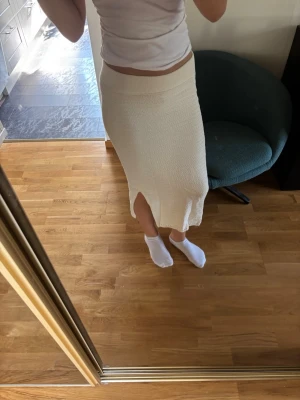 Medellång krämfärgad stickad kjol med slits - Säljer en medellång, krämfärgad stickad kjol med slits framtill. Kjolen har en mjuk och stretchig midja och är perfekt för dig som gillar en enkel men snygg look. Denna kjol är aldrig använd och är ett märke som heter Unig studios, storleken är 170 barn men passar en xs/s tjej