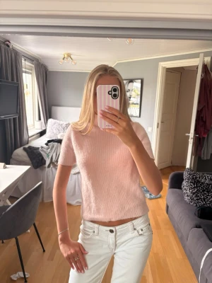 Ljusrosa stickad tröja från MNG - Storlek M men skulle mer säga S eller xs. Söt ljusrosa stickad tröja från MNG med korta ärmar och rund hals. Tröjan har en mjuk och fluffig känsla, perfekt för att addera en feminin touch till din outfit. Passar till både jeans och kjol för en trendig look.