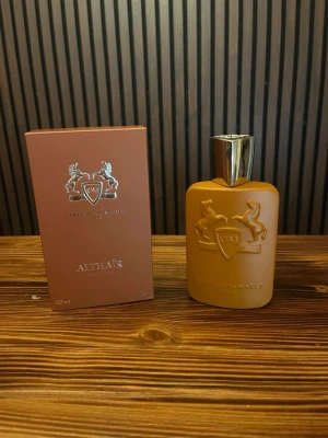 Parfums de Marly Althaïr EdP 125ml - Exklusiv parfym från Parfums de Marly, Althaïr EdP 125ml. Flaskan är matt gulbrun med silverfärgat lock och har ett elegant reliefmönster med två hästar och sköld. Kommer i matchande ask med samma design och lyxig känsla. Helt ny och oanvänd skriv vid frågor!