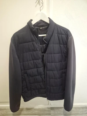 Svart pufferjacka från Zara - Säljer en svart pufferjacka från Zara med quiltad design och ståkrage. Jackan har dragkedja framtill och två sidofickor. Materialet är mjukt och ger en clean look.