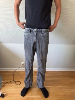 Grå tvättade raka jeans - Säljer ett par grå tvättade jeans med rak passform och klassisk femficksdesign. Jeansen har normal midja och stängs med knapp och dragkedja. Perfekta för en avslappnad och trendig look. Killen är 188 cm 