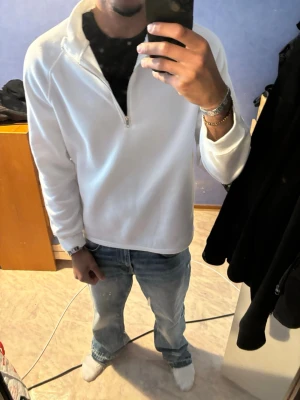 Vit fleece tröja med halv dragkedja - Snygg vit fleece tröja med halv dragkedja framtill och hög krage. Perfekt för lager på lager och chill vardagsstil. Långärmad modell i mjukt material som håller dig varm. Passar till jeans eller mjukisbyxor.