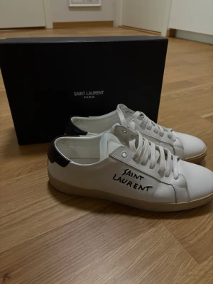 Saint Laurent vita sneakers - Det är egentligen storlek 43 men sitter stora på mig och känns som storlek 44, detta har gjort att jag inte använt de speciellt mycket och även anledningen till att jag säljer vidare de. Skorna är fortfarande fräscha på utsidan, men är lite smutsiga och visar tecken på användning i insidan. Hör av dig vid funderingar!
