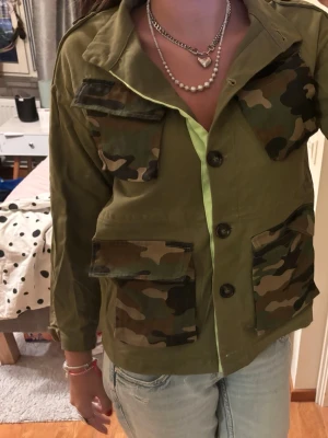 Grön (militär) tunn vår/höst jacka  - As cool jacka med militär detaljer. Tycärr aldirg använd. Köpt i usa. Justeringar på insidan. 