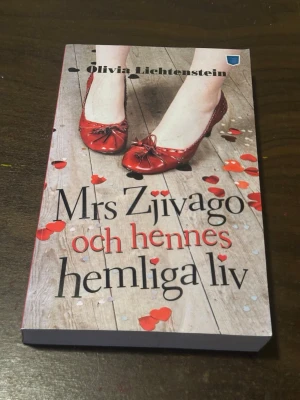 Mrs Zjivago och hennes hemliga liv - En skönlitterär bok av Olivia Lichtenstein. Omslaget visar röda ballerinaskor och hjärtformade konfetti på ett trägolv. Boken handlar om Chloe Zjivago, hennes liv, relationer och hemligheter. Pocketutgåva från Pocketförlaget.