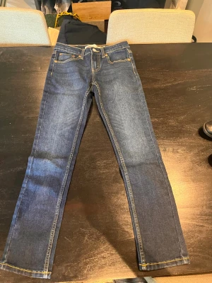 Levi's 512 Slim jeans blå 10A - Snygga blå Levi's 512 Slim jeans i klassisk femficksmodell. Jeansen har smal passform, gul kontrastsöm och är tillverkade i slitstark denim. Perfekta för dig som gillar en tidlös och enkel stil.