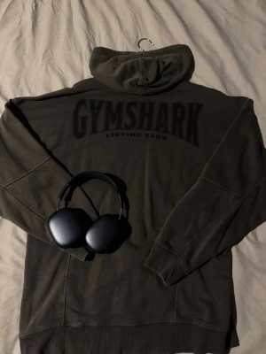  Gymshark hoodie - Snygg hoodie från Gymshark med stort svart 'GYMSHARK Lifting Club'-tryck på ryggen och diskret logga framtill. Klassisk huva och mjukt material som passar perfekt till gymmet eller chill. Oversized fit/Relaxed fit.