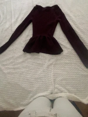 Mörklila topp med volang - Säljer en mörklila topp med lång ärm och snygg volang nedtill. Toppen har en figurnära passform och är perfekt för dig som vill ha något stilrent men ändå med en twist.
