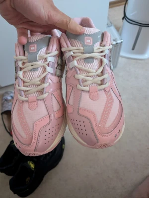 New Balance sneakers - Snygga rosa sneakers från New Balance med vita och grå detaljer. Skorna har mesh- och syntetmaterial i ovandelen, vita snören och en bekväm sula. Perfekta för dig som vill ha en sportig och trendig look. Oanvända.