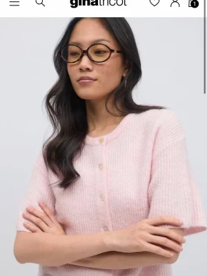 Stickad tröja Gina Tricot  - Supersöt ljusrosa kofta från Gina Tricot med korta ärmar och rund hals. Perfekt att styla med jeans eller kjol eller också ett linne för en chill look🤗