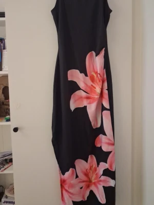 Svart långklänning med stora blommor - Klänningen är från shein. Aldrig använd! Skulle haft den när jag sluta skolan men sen köpte jag en annan som matchade alla andra lite mer. Jätte fin för dig som vill ha en fin look nu i det varma
