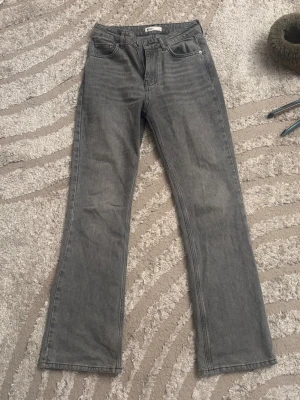 Grå raka jeans med hög midja - Snygga grå jeans med raka ben och hög midja. Jeansen har klassisk femficksdesign och är tillverkade i denim. Perfekta för en avslappnad och trendig look. Bör noteras att de är lite slitna längst ner.