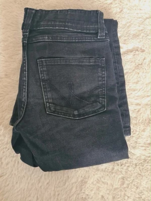 Svarta bootcut jeans - Säljer ett par svarta bootcut jeans med klassisk femficksdesign och utsvängda ben. Jeansen har en mörk tvätt och är sydda i mjukt och stretchig denimtyg. Perfekta för dig som söker stretchiga jeans💕strl 152