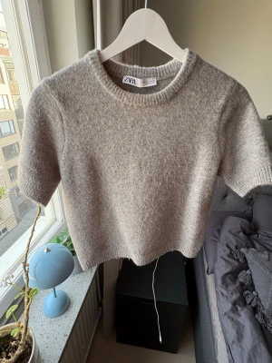 Grå stickad t-shirt från Zara - Kortärmad stickad t-shirt i mjuk grå ullmix från Zara. Den är i väldigt fint skick då den knappt har använts🥰