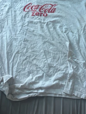 Vit Coca-Cola Zero t-shirt - Vit t-shirt med rött Coca-Cola Zero-tryck på bröstet. Klassisk passform och rund halsringning. Perfekt för dig som gillar retro och ikoniska loggor. Tillverkad i mjuk bomull för skön känsla hela dagen.
