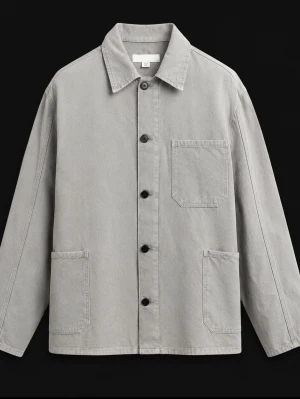 Ljusgrå overshirt med fickor - Stilren ljusgrå overshirt i bomull med klassisk krage och knäppning framtill. Tre utanpåliggande fickor, en på bröstet och två nedtill. Rak passform och långa ärmar. Perfekt lager på lager-plagg för en avslappnad look.