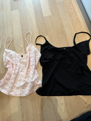 Två linne H&M - Säljer en svart linnetopp med tunna axelband och snygg volangdetalj framtill. Toppen har en enkel och stilren design som passar perfekt till jeans eller kjol. Materialet känns mjukt och lätt mot huden. Sen ett fint ljusrosa spets linne, tunna axelband 